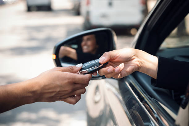 shot of car rental agency employee giving car keys to beautiful young woman.
